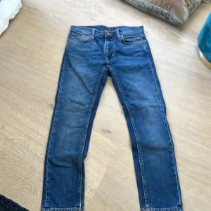 Blå Nudie Jeans straight fit 27/28 - Snygga blå jeans från Nudie Jeans i klassisk straight fit. Jeansen har fem fickor, orangea sömmar. Tillverkade i jeansmaterial med normal passform. de är bara att skriva till mig vid funderingar!