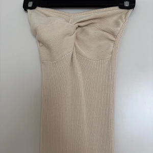 Beige ribbad långklänning Bik Bok XS - Supersnygg beige ribbad långklänning från Bik Bok by Lovisa Barkman. Klänningen är axelbandslös med twistad detalj upptill och har en slits nertill för extra vibe. Perfekt för dig som gillar en tight och stilren look.