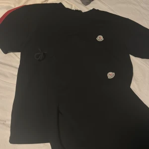 Moncler shorts set - Svarta mjukisbyxor från Moncler med elastisk midja och snygga röda, vita och blå ränder längs sidorna. Byxorna har Moncler-logga framtill och är perfekta för en sportig och stilren look. Sköna och lätta att bära till vardags.