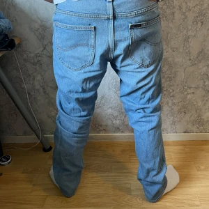 Ljusblå Lee jeans W30 L30 - Säljer ett par klassiska ljusblå jeans från Lee i rak modell. Jeansen har fem fickor, snygga kontrastsömmar och Lee-logga på bakfickan. Tillverkade i slitstarkt bomullsjeans, perfekta för dig som gillar en tidlös look.