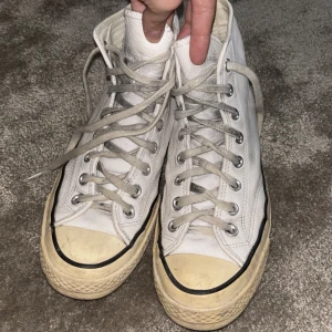 Vita Converse Chuck Taylor All Star - Klassiska vita/ljusljusblåa Converse Chuck Taylor All Star high-tops i skinn med rund tå och snörning. Snygg retrostil med svart rand runt sulan och logga på sidan. Perfekta för dig som gillar tidlösa skor. Använda men inte slitna!🩵 Tvättar innan det skickas!