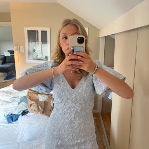 Ljusblå brokadklänning Gina Tricot - Supersöt ljusblå brokadklänning från Gina Tricot med v-ringning och puffiga korta ärmar. Endast testad