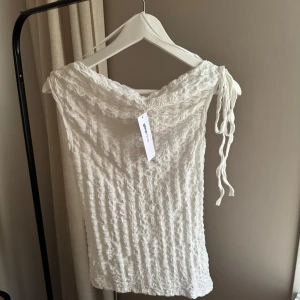 Vit asymmetrisk topp med struktur - Gina Tricot - Säljer en vit strukturerad topp från Gina Tricot i asynmmetrisk modell med oneshoulder och knytband på axeln. structure asymmetric top med en knyt detalj på ena axeln . 🥰 Ord pris: 279,95kr (numera slutsåld) Perfekt att styla med jeans eller kjol för en trendig vibe.