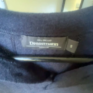 Svart pikétröja från Dressmann S - Säljer en stilren mörkblå pikétröja från Dressmann i storlek S. Tröjan har klassisk krage, knäppning med två knappar och korta ärmar. Perfekt till jeans eller chinos för en clean look.