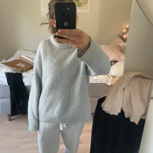 Ljusgrå stickad tröja från Zara - Supermjuk och oversized ljusgrå stickad tröja från Zara. Tröjan har rund halsringning, långa ärmar och breda ribbade muddar. Perfekt för lager-på-lager och chill dagar. Enkel att matcha med jeans eller mjukisbyxor.