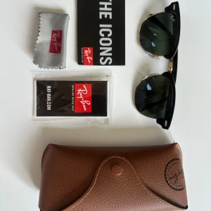 Ray-Ban Clubmaster Solglasögon  - Ray-Ban Clubmaster RB3016 med klassisk svart båge och guldiga detaljer. Snygg retroform med gröna glas. Kommer med originalfodral, putsduk och Ray-Ban certifikat. Perfekt accessoar för en cool och tidlös stil.