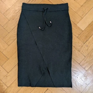 Kjol - Mörkgrön kjol från BikBok i mjukt stickat material med dragsko i midjan. Kjolen är rak och har en snygg omlott-detalj framtill. Perfekt för dig som gillar en clean och stilren look. Jättefin kjol i härligt tjockt och stretchigt i material.