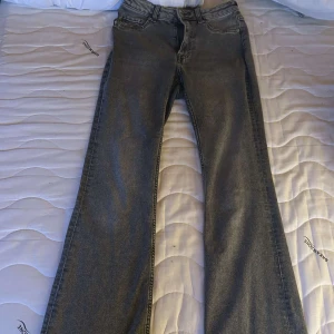 Grå bootcut jeans från H&M Divided - Snygga grå jeans från H&M Divided i bootcut-modell. Jeansen har klassisk femficksdesign, normalhög midja och raka ben med lätt utsvängd nederdel. Tillverkade i mjukt denimtyg som sitter skönt hela dagen. Dom har lite slitningar på baksidan längst ner som i sista bilden men det är inget man tänker på.