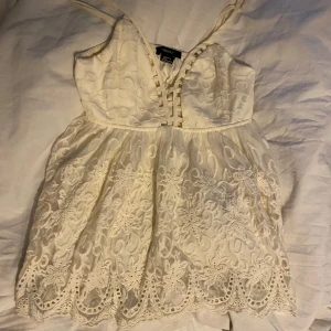 Vit spetslinne från Forever 21 - Supersött vitt linne från Forever 21 med tunna axelband och v-ringning. Toppen har broderade spetsdetaljer och blommönster över hela tyget samt en vågig kant nedtill. Perfekt för sommaren och midsommar! Skriv för frågor eller fler bilder!🌷☀️🥰