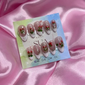 Strawbabe(XS);Medium Almond - Supergulliga gelé press on-naglar i en medium mandelform med ljusrosa bas och handmålade röda jordgubbar, gröna blad och silvriga detaljer. Kommer i storlek XS: 14 mm, 11 mm, 11,5 mm, 10 mm, 8 mm. Perfekt för dig som vill ha unika och färgglada naglar utan att gå till salong.
