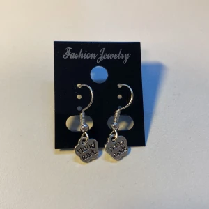 Unika, Handgjorda Silvriga örhängen med handgjorda berlocker *Endast 1 Kvar* - Snygga silvriga örhängen med små blommiga berlocker där det står 'Hand made'. Hängande modell med krok, perfekt för dig som gillar unika detaljer. Passar till alla tillfällen när du vill sticka ut lite extra.