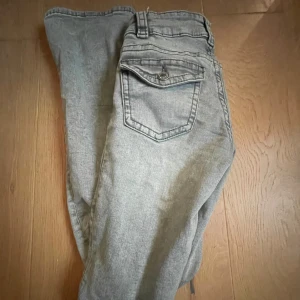 Gråa lågmidjade jeans med fickor bak - Jätte fina gråa jeans från Gina tricot. Jeansen är lågmidjade och har utsvängda ben. Dom har ett hål på knät som jag själv har gjort och jag tyckte att det blev finare, och mer åt Stockholmsstil hållet. Köpte dom för ungefär ett år sedan men är i ett extremt bra skick❣️❣️