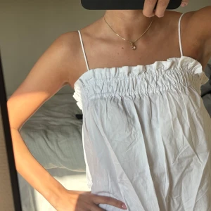 Vit kort klänning från H&M XS - Supersöt vit kort klänning från H&M i storlek XS. Klänningen har smala justerbara axelband och rynkad resår upptill som ger en luftig och avslappnad känsla🤍🤍🤍