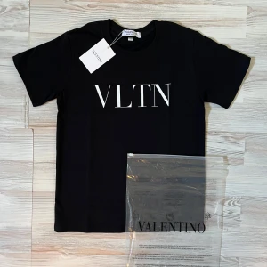 Svart Valentino t-shirt med VLTN-tryck - Snygg svart t-shirt från Valentino med stort vitt VLTN-tryck på bröstet. Klassisk rund hals och korta ärmar. Tillverkad i mjuk bomull för en skön känsla och stilren look. Perfekt för dig som gillar exklusiva märken och enkel design.