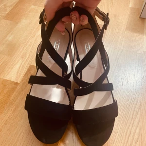 Svarta sandaler från 5th Avenue - Stilrena svarta sandaler med korsade remmar och låg klack från 5th Avenue. Skorna har öppen tå, dragkedja bak och är gjorda i mocka för en lyxig känsla. Perfekta för dig som gillar en enkel men trendig look. Använt 1 gång. Klicka på köp så skickar jag inom 1-2 dagar 💓