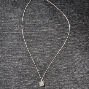 Silver halsband - Ett tunt silverhalsband med ett hängsmycke i form av en glittrande snöflinga. Hängsmycket har en detaljrik design med små stenar som ger extra bling. Perfekt för dig som gillar stilrena och eleganta smycken med lite extra sparkle.