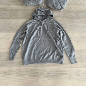 Grå kashmir hoodie - Snygg grå hoodie med huva och snörning framtill. 