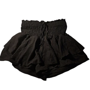 Volangkjol nytt - En svart volangkjol med hög midja och resår. Inbyggda shorts