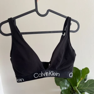 Svart Calvin Klein linnetopp M - Svart linnetopp från Calvin Klein med klassisk logga i vitt på det elastiska bandet under bysten. Justerbara axelband och mjukt bomullsmaterial gör den superbekväm. Helt oanvänd.