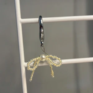 Nyckel knippa  med pärlrosett i silver - Supergullig nyckel knippa med en rosett av vita pärlor och en större pärla i mitten. Hängs på en silvrig ring som ger en stilren touch. Perfekt accessoar för att lyfta din väska med något unikt och sött. Egen gjord!