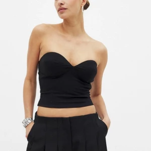 Svart axelbandslös korsettliknande - Topp med resår i bak. Aldrig använd. Nypris 399:-