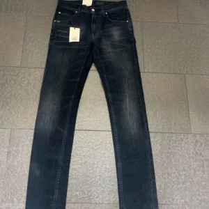 Slim jeans från Tiger of Sweden - Snygga mörkblå jeansbyxor från Tiger of Sweden med klassisk femficksdesign och diskret slitning på låren. Jeansen har raka ben och normal passform, tillverkade i mjukt denimtyg. Perfekta för dig som gillar stilrena och tidlösa jeans.
