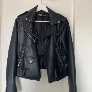 Svart skinnjacka från Zara med bälte - Snygg svart skinnjacka från Zara. Kommer inte till användning längre.