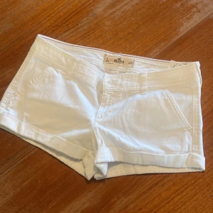 Vita shorts från Hollister - Snygga vita shorts från Hollister med klassisk femficksdesign och uppvikta benslut. De har två fickor fram och två bakfickor med knapp, samt diskret Hollister-logga bak. Perfekta för varma dagar och riktigt fräsch stil.