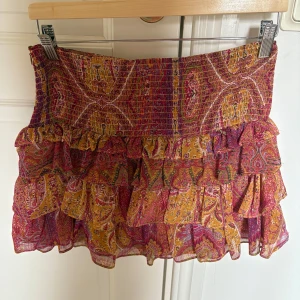 Färgglad volangkjol från Zara - Kort volangkjol från Zara med paisleyinspirerat mönster i rosa, gult och rött. Använt få gånger o är i storlek m men passar även s. Lätt och luftig i tunt tyg.