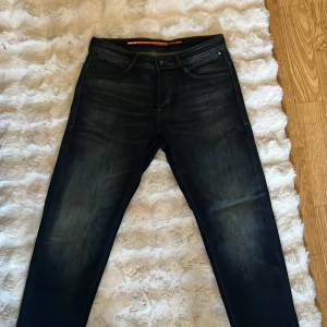 Mörkblå jeans från Jack & Jones - Snygga mörkblå jeans från Jack & Jones med klassisk femficksdesign och diskreta slitningar framtill. Jeansen har raka ben och normal passform, tillverkade i slitstarkt denimtyg. Perfekta för en avslappnad och stilren look. Har inte använts en ända gång då jag fick de i present men var för stora. Priset är diskuterbart.