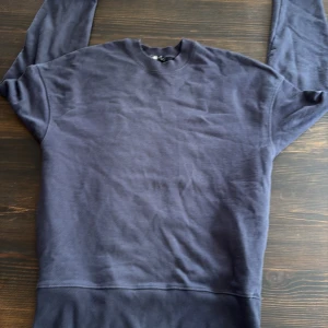 Mörkblå sweatshirt från Zara - En basic mörkblå sweatshirt från Zara i storlek S. Tröjan har rund halsringning, långa ärmar och ribbade muddar vid ärmslut och nederkant. Perfekt för en chill och avslappnad stil. Tillverkad i mjuk bomullsmix för extra komfort.