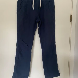 Mörkblå linnebyxor från Lindex - Mörkblå linnebyxor från Lindex med dragsko i midjan och raka ben. Byxorna har sidfickor fram och passpoalfickor bak. Perfekta för en chill och avslappnad stil, tillverkade i svalt linne.