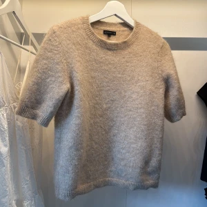 Beige stickad tröja från Stockh lm - Supermjuk och fluffig beige stickad tröja från Stockh lm. Tröjan har korta ärmar, rund halsringning. Enkel och stilren design som är lätt att matcha.