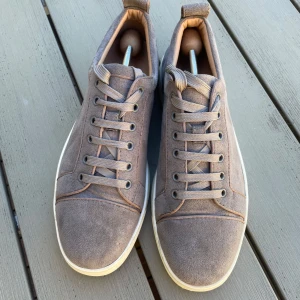 Grå mockasneakers från Louboutin - Säljer ett par äkta Christian Louboutin sneakers i grå mocka, storlek 42. Ikonisk röd sula och stilren design. Bra begagnat skick med visst slitage på sulan, ovandelen är fräsch. Perfekta till både vardag och finare tillfällen. Nypris ca 8 000 kr. Fraktas välpackat. Hör av dig vid frågor!