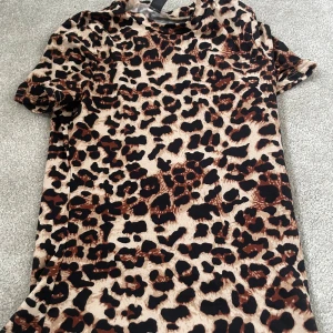 Leopardmönstrad topp från SHEIN XS - Cool topp från SHEIN i storlek XS med leopardmönster i beige, brunt och svart. T-shirten har korta ärmar och är gjord i ett mjukt, stretchigt syntetmaterial.