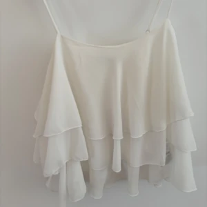Vit volangig linnetopp - Supersöt vit linnetopp med tunna axelband och flera lager av volanger! Perfekt nu till sommaren!!😍😍🤍