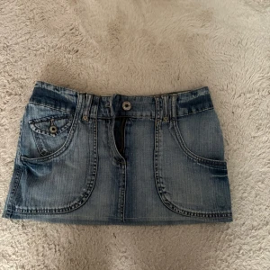 Blå jeanskjol med fickor - Snygg kort jeanskjol i ljusblå denim med coola detaljer som stora framfickor, bakfickor och bälteshällor. Kjolen är aldrig använd därav den är för liten💕