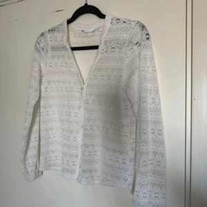 Vit spetsblus med lång ärm - Säljer en superfin vit blus i spets med v-ringning och långa ärmar. Blusen har ett detaljerat spetsmönster över hela och är perfekt för dig som gillar romantisk och luftig stil. Passar snyggt till både jeans och kjol.