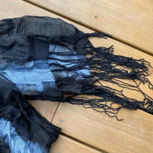 Svart och blå randig halsduk med fransar - Svart sjal med silverdetaljer och fransar. Elegant och stilren, perfekt för att komplettera din outfit. Mått: 172x25 cm  Inga bilder när den sitter på mig! Katter finns i hemmet!