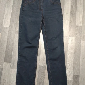 Mörkblå jeans från Magic Stretch - Snygga mörkblå jeans från Magic Stretch med klassisk femficksdesign och dekorativa sömmar på bakfickorna. Jeansen har raka ben och kontrastsömmar som ger en stilren look. Perfekta för dig som gillar en enkel men trendig stil.