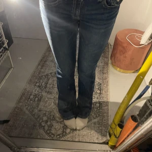 Gina jeans low waist - Säljer ett par klassiska blå jeans med bootcut-modell och low waist, samt fem fickor och tydliga sömmar. Perfekta för dig som gillar en tidlös och avslappnad stil.