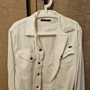 Vit denimjacka  från Nudie Jeans Co i str M - Snygg vit denimjacka i str M från Nudie Jeans Co i bomull. Perfekt lager-på-lager-plagg med lång ärm och stilren look. 