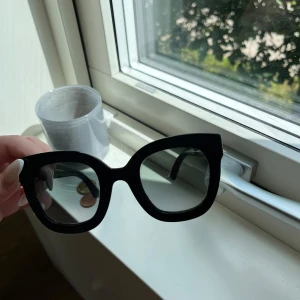 Svarta cat eye-solglasögon  - Snygga svarta solglasögon  med cat eye-formade bågar. På sidorna finns guldfärgade  och två silvriga stjärnor som ger en extra touch. Glasögonen har mörka linser och en chunky design som verkligen sticker ut.