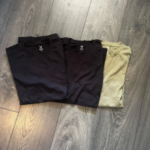 Svart och grön t-shirt SOC & H&M 3- PACK - Tre basic t-shirts i storlek S, två svarta från SOC och en olivgrön från H&M. Alla har rund halsringning och klassisk passform. Perfekta för en clean och enkel stil. Tillverkade i mjuk bomull som känns skön mot huden.
