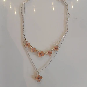 Sött blommigt halsband i silverfärg - Sött , silvrigt halsband med små rosa blommor. Halsbandet är dubbetkedjat.