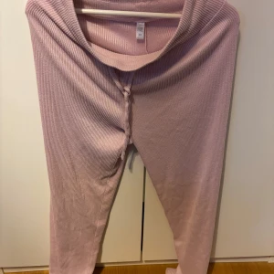 Ljusrosa ribbade mjukisbyxor - Supermysiga ljusrosa mjukisbyxor med ribbad struktur och snörning i midjan. Perfekta för chill hemma eller när du vill vara bekväm men ändå se söt ut. Mjukt material och relaxed fit.