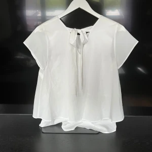 Blus med rosett - Tunt och skönt material, rosett baktill i nacken. Ganska genomskinligt material så det finns ett extra lager tyg under. 