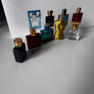 Parfymset med Versace & Jean Paul Gaultier - Säljer ett parfymset med fem miniflaskor: tre fyrkantiga Versace-flaskor i blått, rött och turkost glas med gulddetaljer, en genomskinlig flaska med guldkrona samt en ikonisk guldig Jean Paul Gaultier-flaska formad som en torso alla Versace parfymer är storsätt helt fulla och guldiga Jean Paul parfymen är vid midjan och Jean Paul dcamdsm är lite mindre än hälften alla luktar super gott .