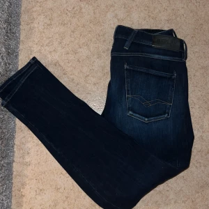 Blå Replay Anbass Jeans herr - Säljer ett par klassiska blå jeans från Replay med raka ben och snygga detaljer på bakfickorna. Jeansen har normal passform och är tillverkade i slitstarkt denim. Perfekta för dig som gillar stilrena och tidlösa jeans. Mycket bra skick, sitter bra och så. Mitt pris 400kr. Kontakta mig om du har frågor.