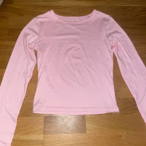 Ljusrosa långärmad topp - Enkel och stilren ljusrosa långärmad topp i mjuk bomull. Perfekt att matcha med jeans eller kjol för en clean look. Rund halsringning och normal passform gör den superbekväm att bära hela dagen.